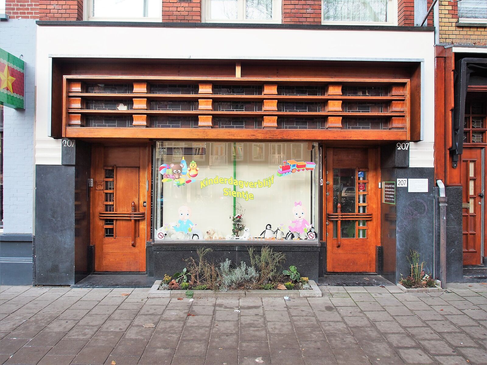 The Art Deco wooden shopfront of a small daycare on Ceintuurbaan in Amsterdam, with children's paper decorations in the window