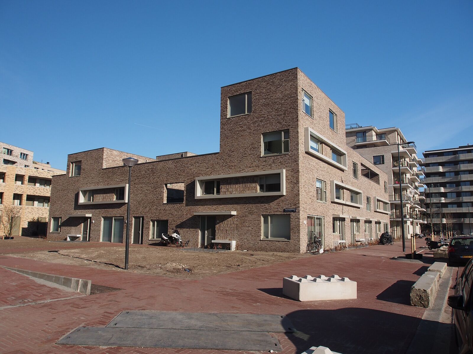 Newly built brick row houses and apartment blocks around a paved square in IJburg, Amsterdam