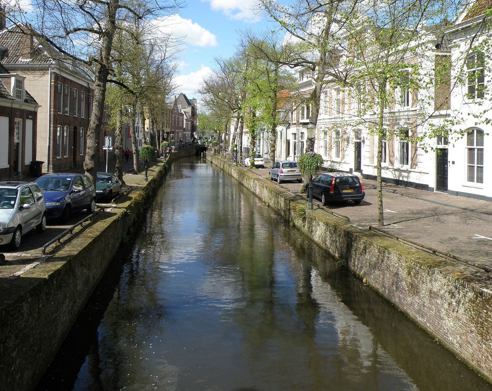 Historic white and brick houses along the narrow Kortegracht canal in Amersfoort, with cars parked on both quays
